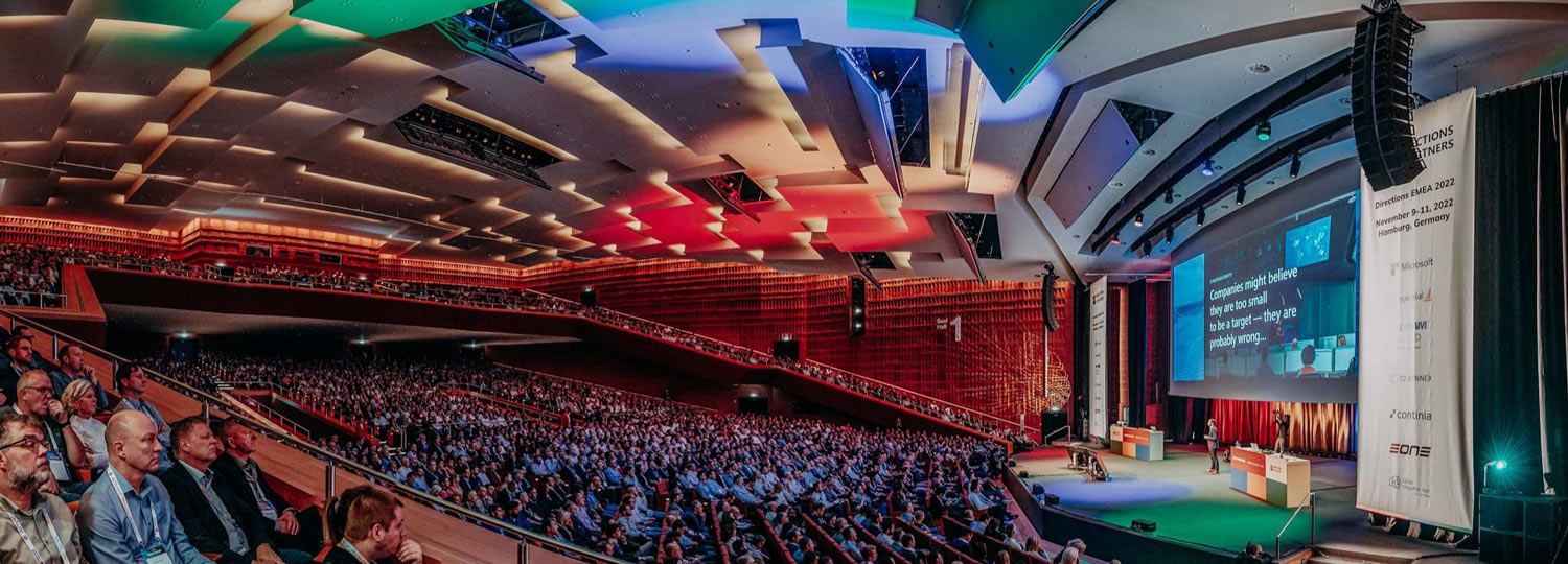 CCH EMEA Großer Konferenzsaal mit vielen Zuschauern, Vortragenden auf Bühne und Präsentation auf Leinwand
