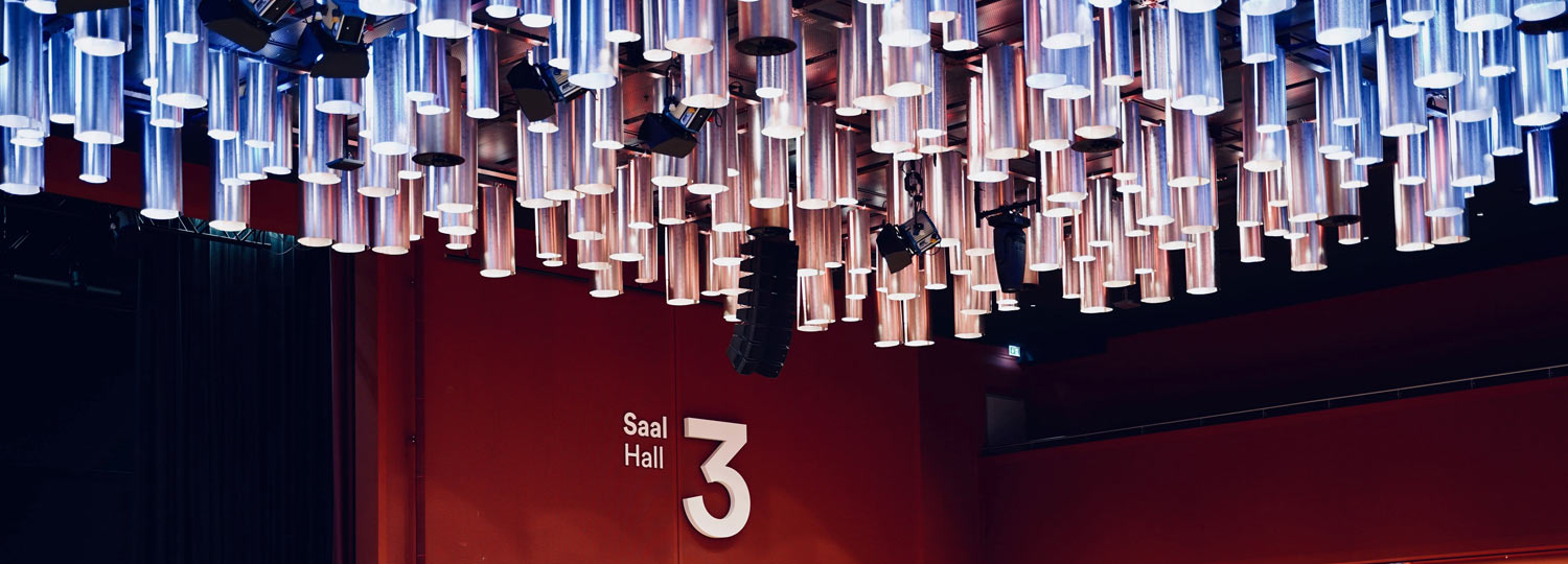 CCH Moderner Saal mit roter Wand, großer Zahl 3, Leuchtröhren und Scheinwerfern an der Decke