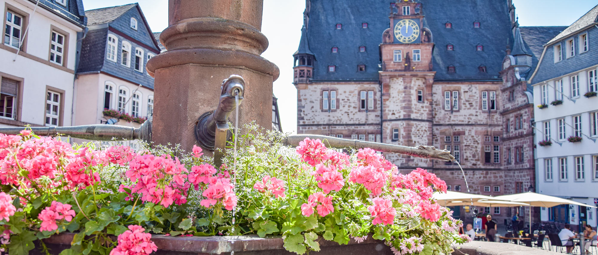 Historischer Marktplatz mit Blumenschmuck, Brunnen und altem Rathaus im Hintergrund