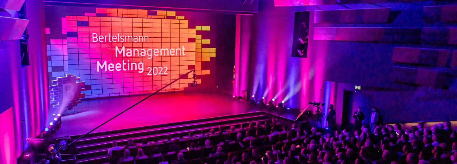 Bunte Bühne mit Schriftzug Bertelsmann Management Meeting 2022 und Publikum im Zuschauerraum