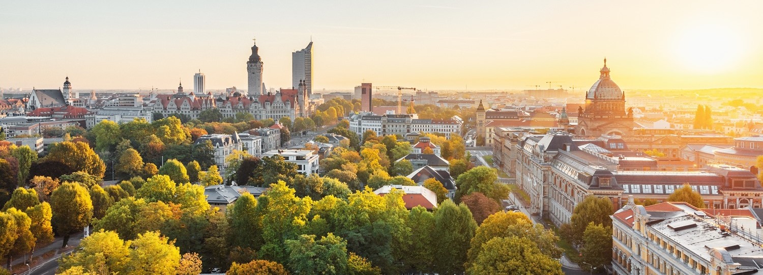 Stadtpanorama von Leipzig mit markanten historischen Gebäuden und viel Grün bei Sonnenuntergang