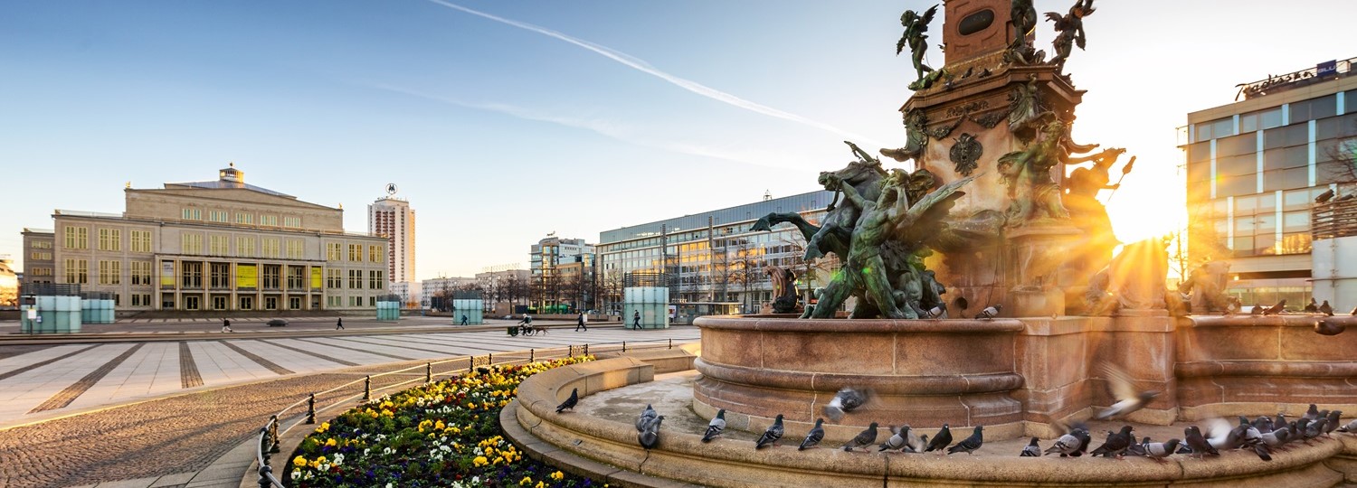 Marktplatz mit Brunnen, Opernhaus und moderner Architektur in Leipzig bei Sonnenaufgang