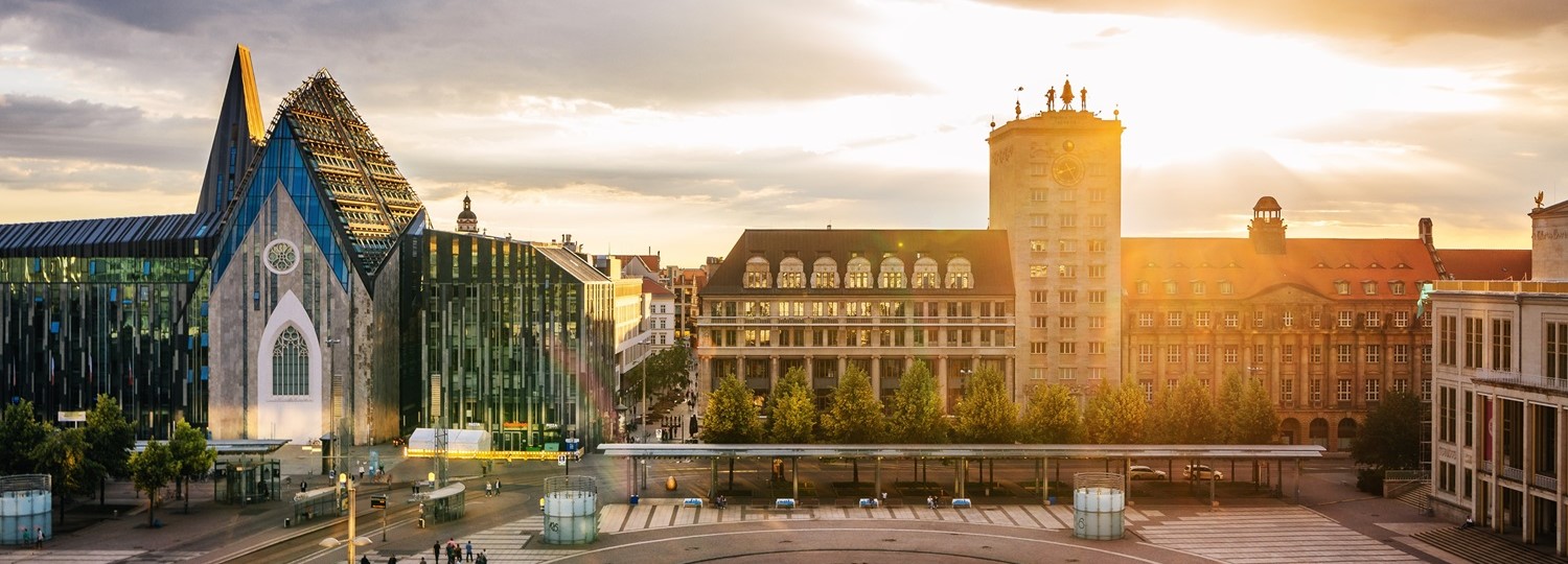 Panorama vom Augustusplatz in Leipzig mit moderner Universitätskirche und historischen Gebäuden bei Sonnenuntergang