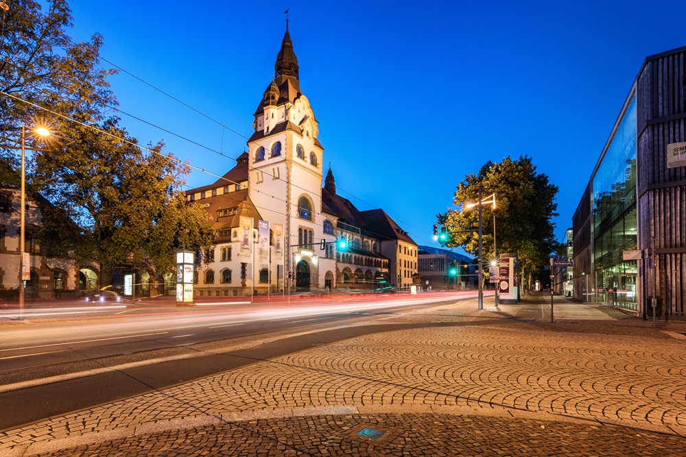 Abendstimmung in einer Stadt mit historischem Gebäude, beleuchteten Straßen und moderner Architektur